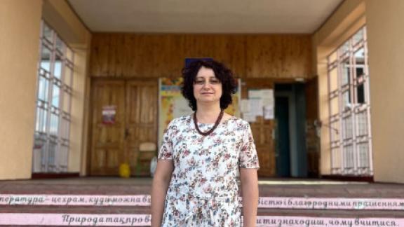 Principal Olena stands on the steps of her refurbished elementary school