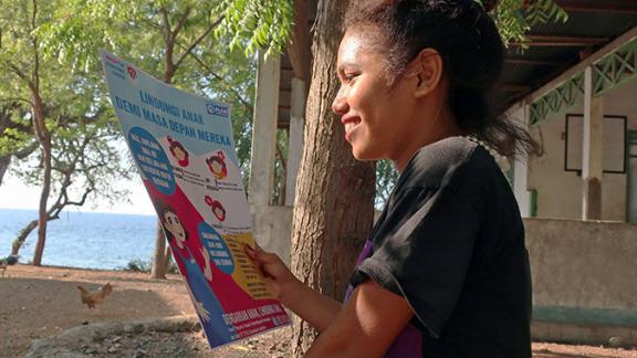 In Indonesia, Monika holds one of our child protection posters