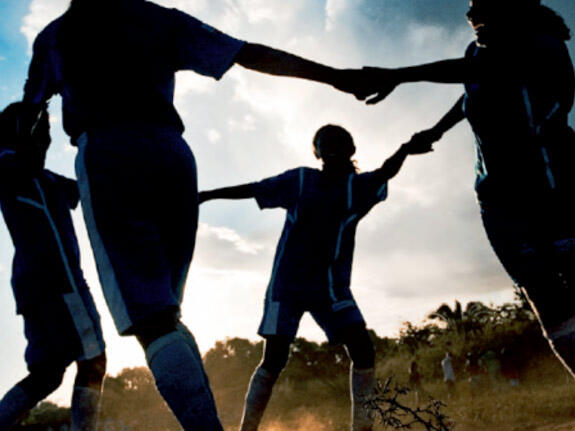 Children holding hands dancing in a circle