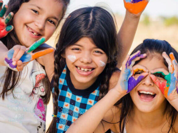 A group of young girls with face paint on smile at the camera