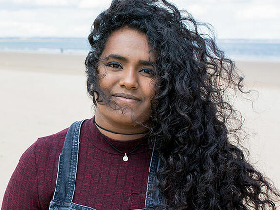 A girl standing on a beach in the UK smiling at the camera