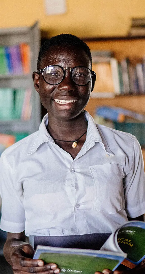 Moreen, 19, reads one of the books from her school library in Uganda.