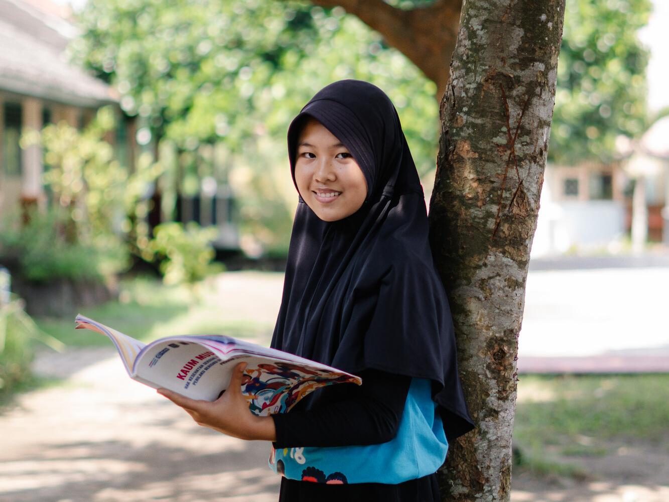 Adiana, 13, holding an education pack about child marriage, distributed by Plan International