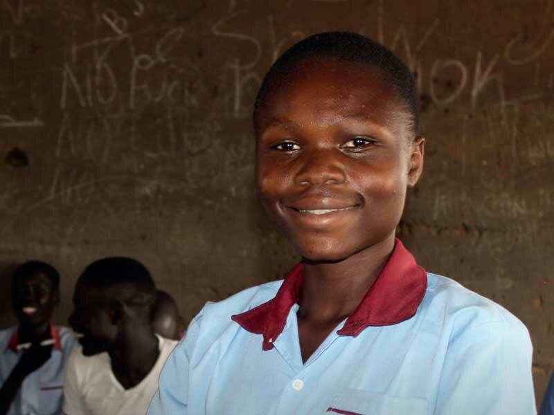 Girl smiling at camera standing in classroom