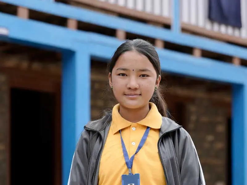 Lakshina standing in front of school looking at camera